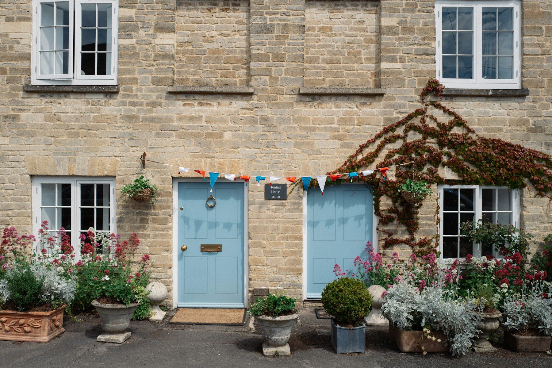 Stone cottages with pale blue front doors and flower tubs
