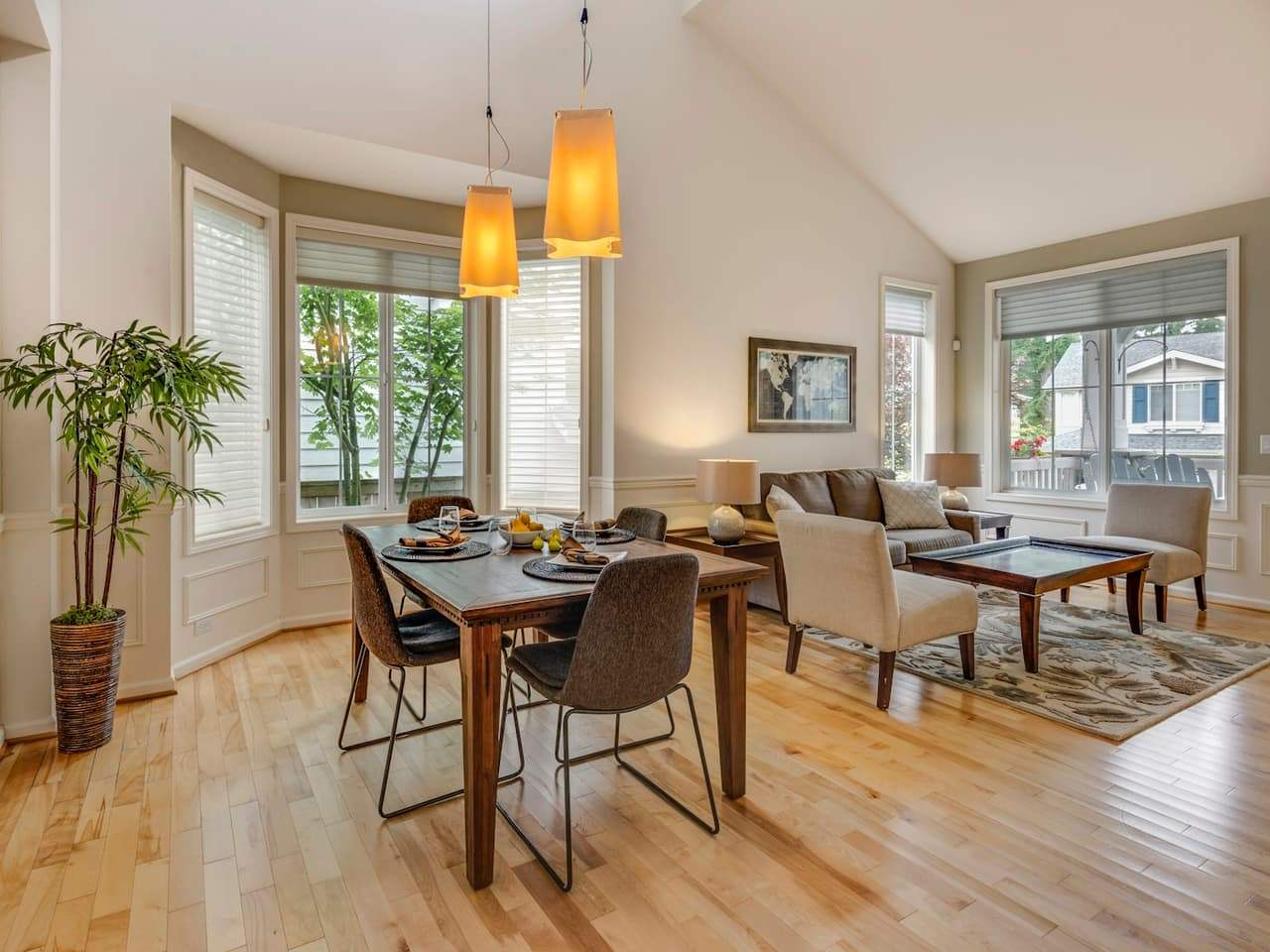 A warm, light-filled cottage living and dining room with timber floors and soft lamplight.