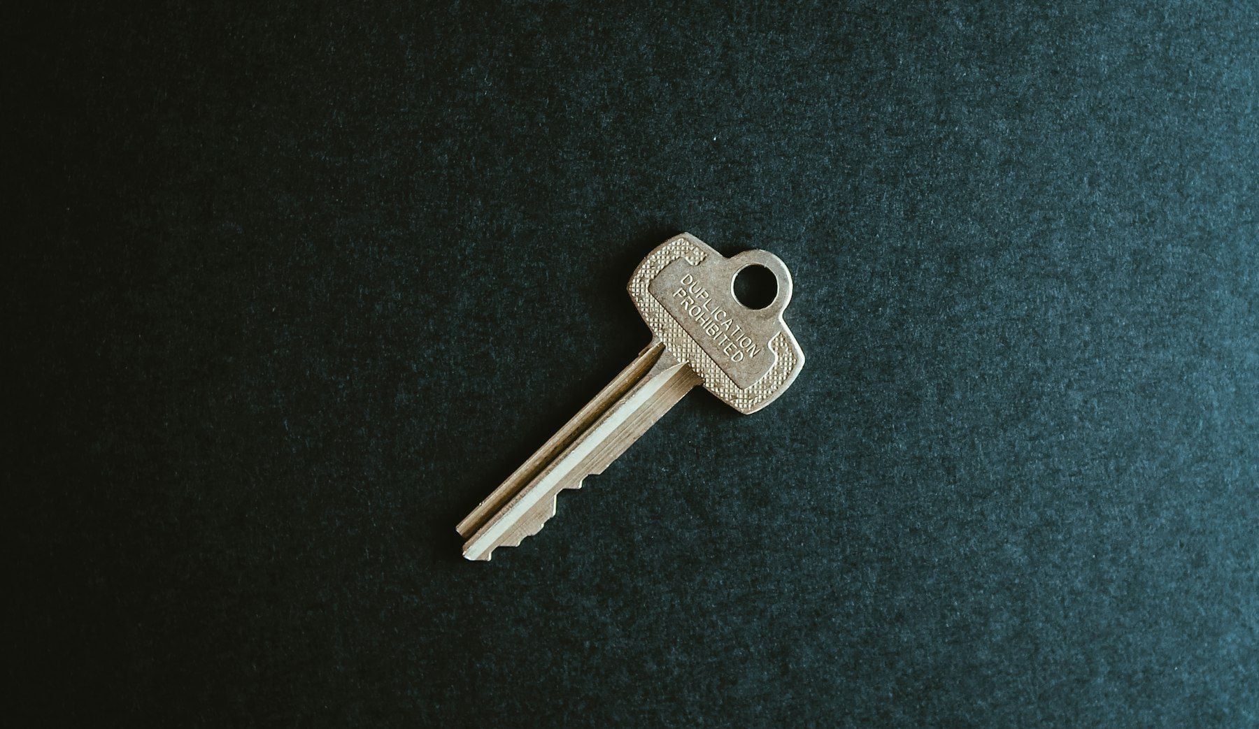 A single key resting on dark slate